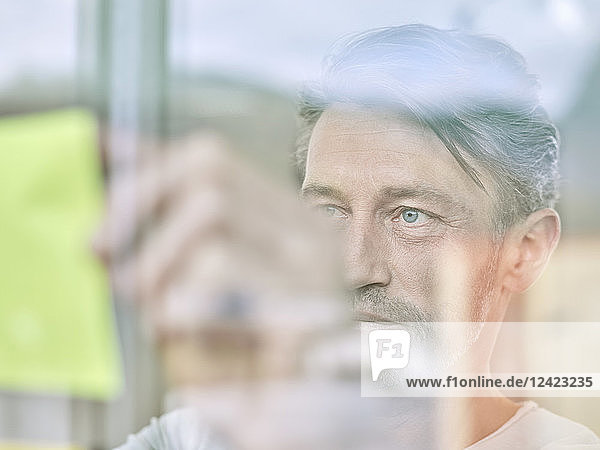 Businessman looking at sticky note at glass pane