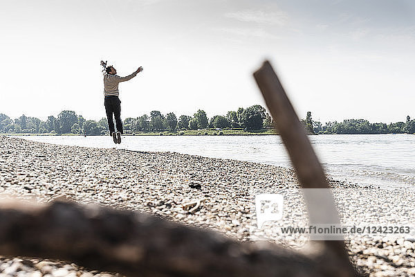 Mature man jumping in the air at Rhine riverbank