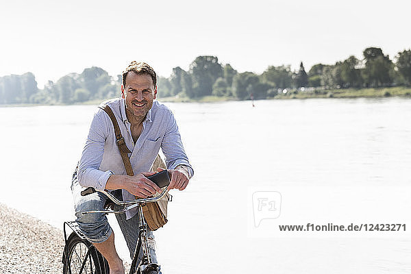 Mature man with bike and smartphone at Rhine riverbank