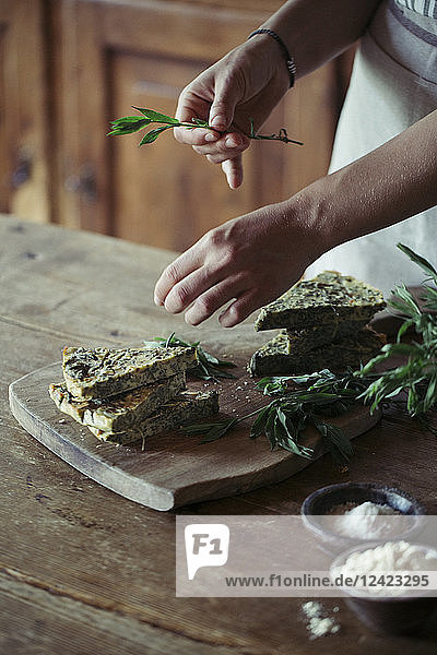 Young woman garnishing homemade chickpea and herb cake