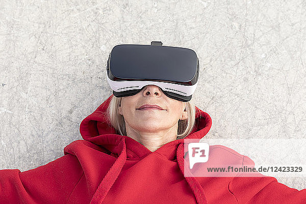 Senior woman lying on the ground wearing VR glasses