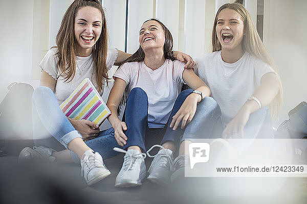 Happy teenage girls sitting on floor in school