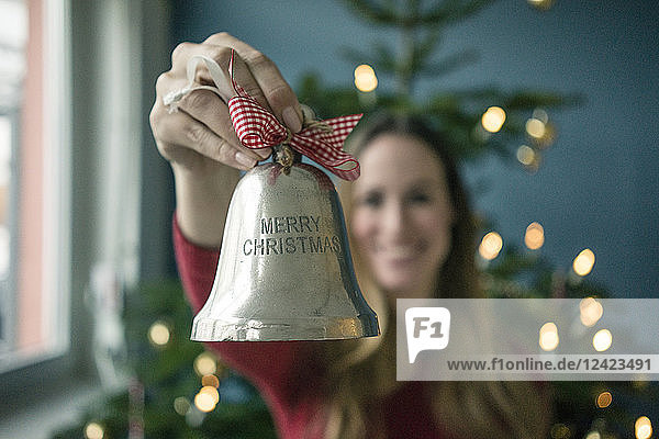 Woman's hand holding silver Christmas bell