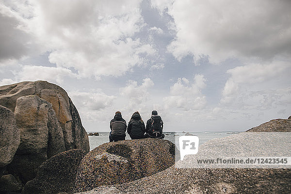 France  Brittany  Meneham  friends sitting on rock formation at the coast