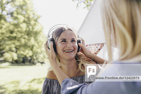 Two happy young women with headphones in a park