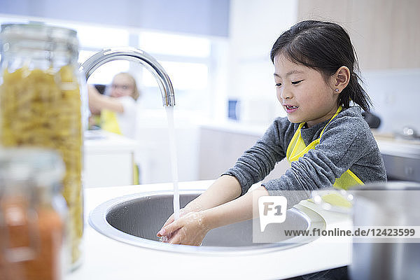 Schoolgirl washing her hands in cooking class