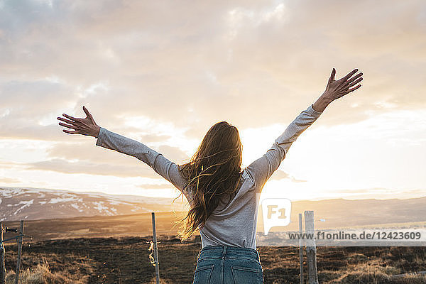 Iceland  young woman with raised arms at sunset