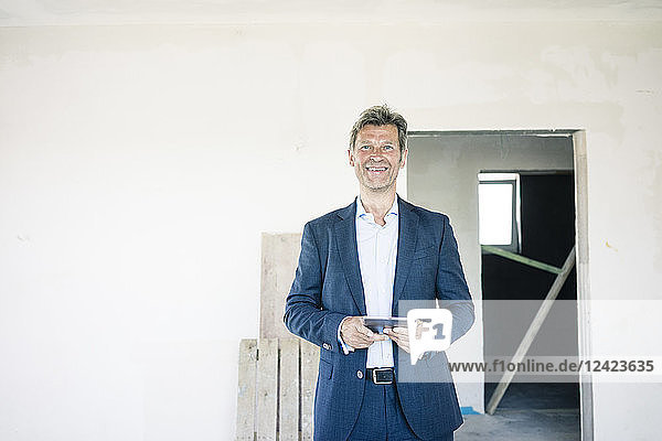 Portrait of smiling man in suit in building under construction