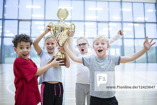 Happy pupils holding trophy in gym