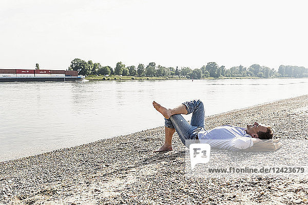 Mature man lying at Rhine riverbank