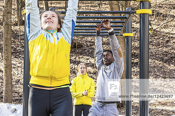 Friends exercising at monkey bars in a park