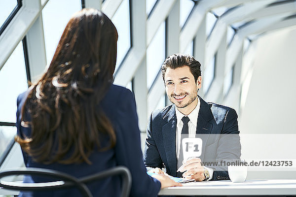 Smiling businessman looking at businesswoman in modern office