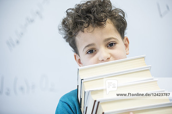 Portrait of schoolboy carrying books in class