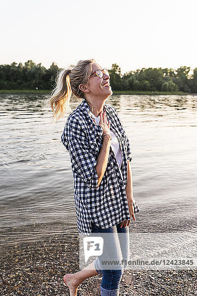 Laughing young woman walking on riverside in the evening