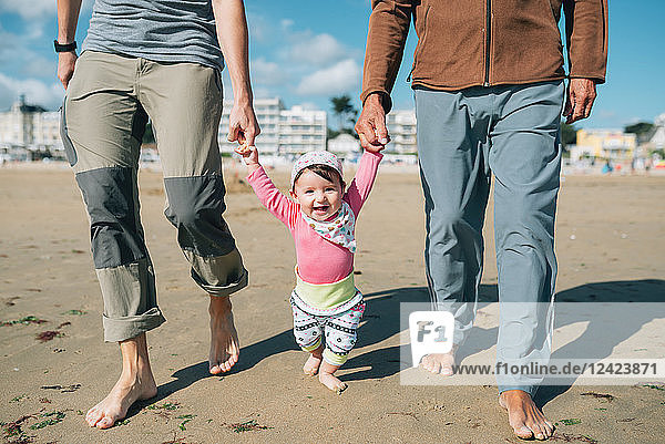 France  La Baule  portrait of happy baby girl walking on the beach with father and grandfather