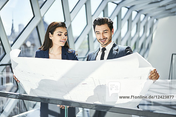 Smiling businesswoman and businessman looking at plan in office