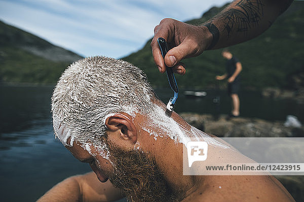 Norway  Lofoten  Traveller getting his head shaved at lake