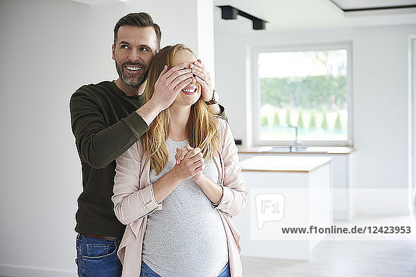Man surprising pregnant woman in empty flat
