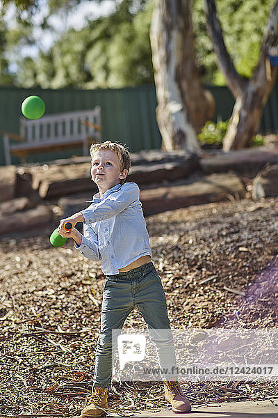 Boy in garden playing with foam baseball bat and ball