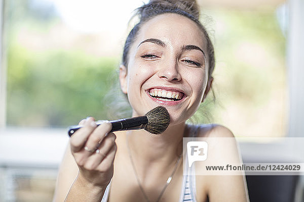 Happy teenage girl applying makeup