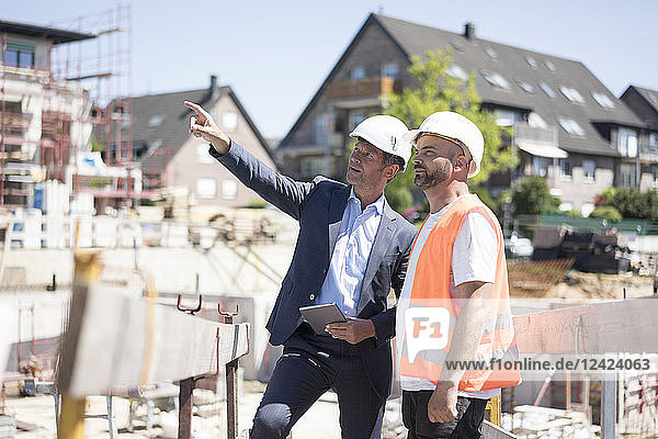 Man in suit talking to construction worker on construction site