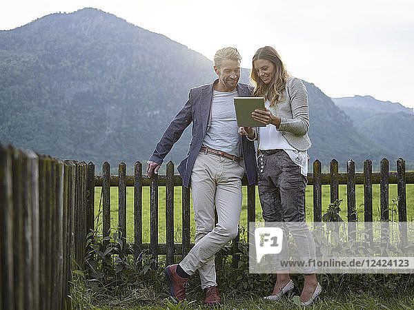 Man and woman sharing tablet in rural landscape
