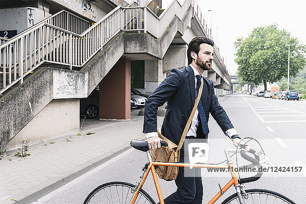 Businessman with bicycle walking on the street