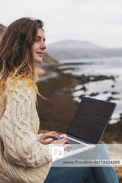 Iceland  woman using laptop at the coast
