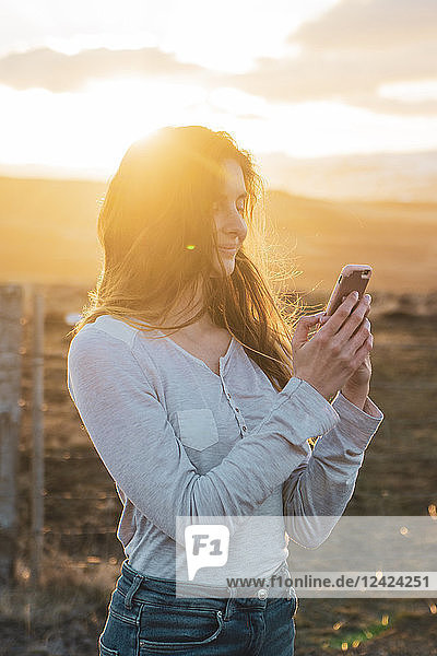 Iceland  woman using smartphone at sunset