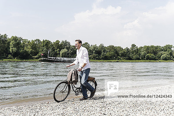Mature man with bike at Rhine riverbank