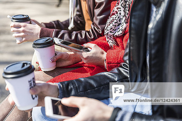Russia  Moscow  details of three friends holding smartphones and coffee to go