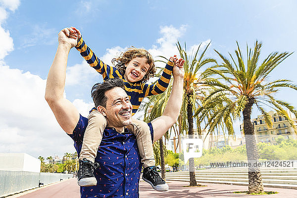 Spain  Barcelona  happy father carrying son on shoulders