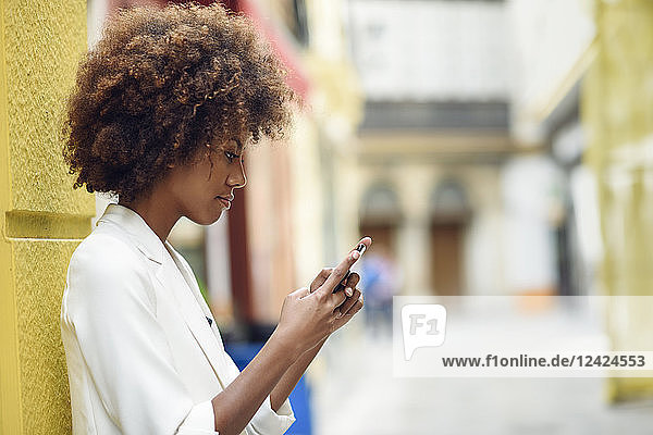 Young woman with curly brown hair looking at cell phone