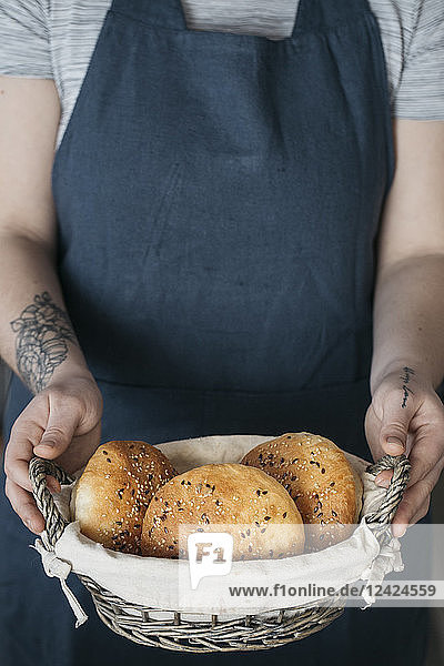 Woman holding basket with homemade vegan bread rolls
