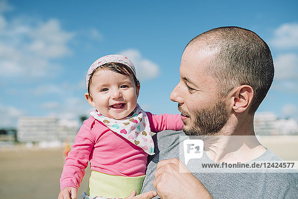 France  La Baule  portrait of smiling baby girl on father's arms on the beach