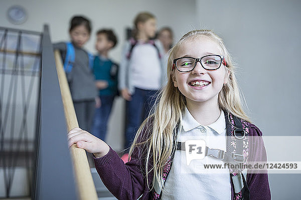 Portrait of happy schoolgirl with classmates on staircase leaving school
