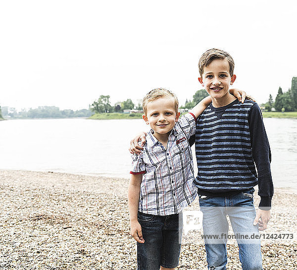 Portrait of two smiling boys embracing at the riverside