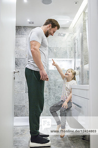 Father and daughter checking weight on bathroom scales