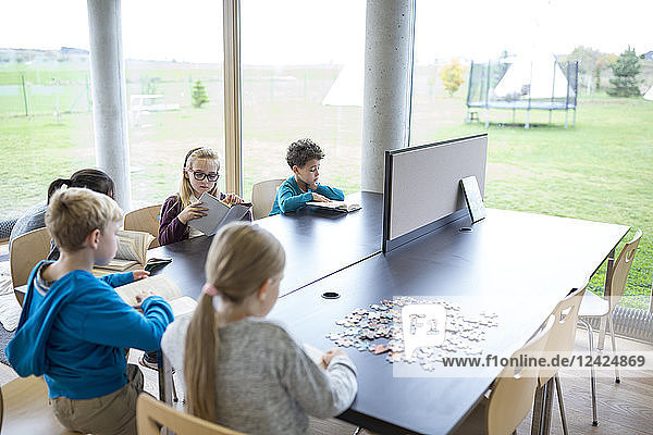 Pupils reading books on table in school break room
