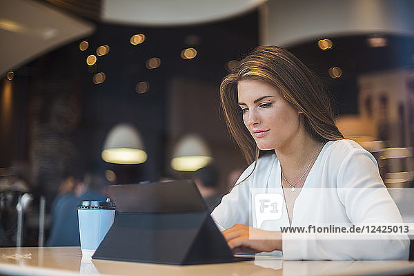 Young businesswoman in a cafe using tablet
