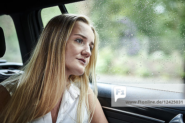 Serious blond young woman in a car at a rainy day