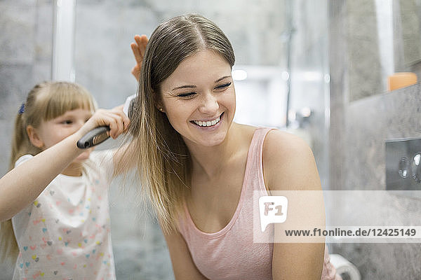 Little girl brushing her mother's hair