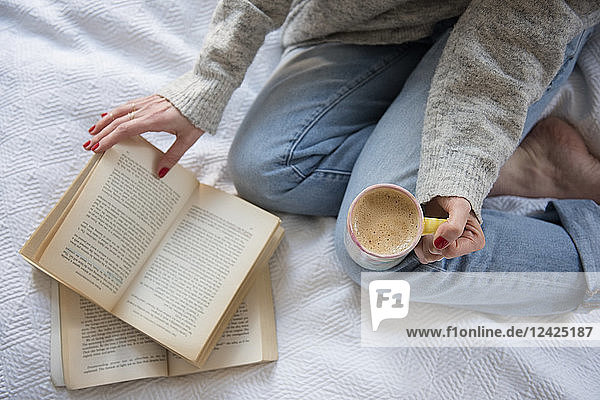 Frau im Bett mit Kaffee und Buch