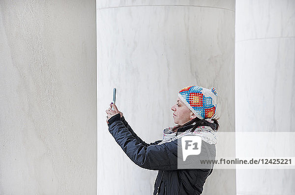 Frau fotografiert mit Smartphone an Säulen