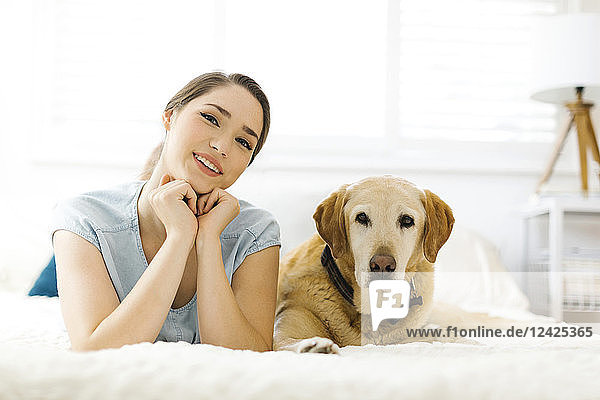 Woman lying on bed with dog