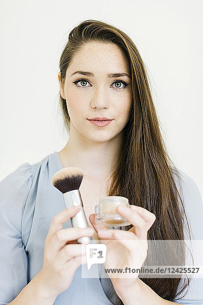 Woman holding powder and make up brush