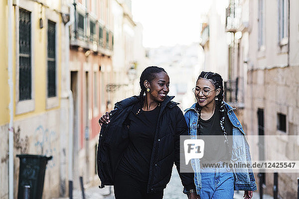 Portugal  Lissabon  Zwei lächelnde junge Frauen gehen im Freien spazieren