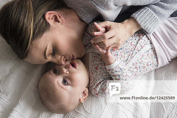 Mother kissing baby girl (18-23 months) with care