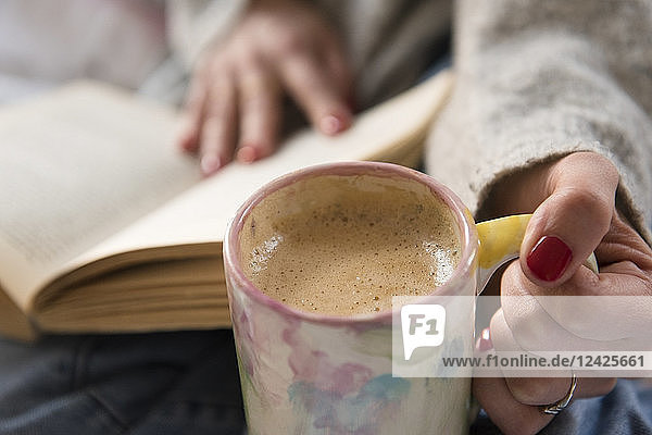 Nahaufnahme einer Frau mit Kaffee und Buch