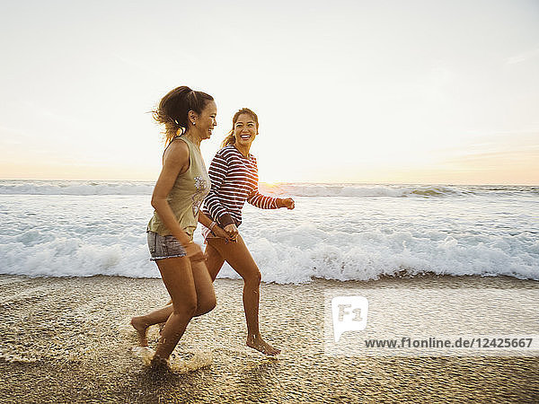 Mutter und Tochter joggen am Strand